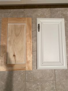 two white cabinets sitting on top of a tile floor next to a wooden cabinet door