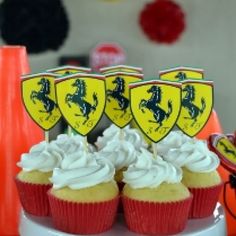 cupcakes with white frosting and yellow emblems on them sitting on a plate