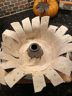 a white flower shaped object sitting on top of a black counter next to a pumpkin