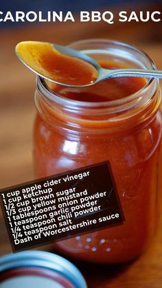 a jar filled with liquid sitting on top of a wooden table next to a spoon