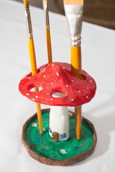 three brushes are sitting on top of a mushroom shaped stand with paintbrushes sticking out of it