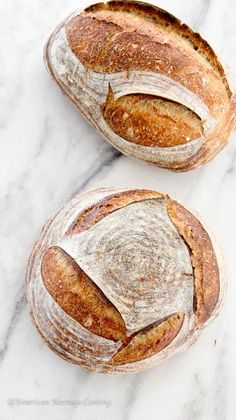 two loaves of bread sitting on top of a white marble countertop next to each other