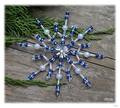 a snowflake ornament with blue and white glass beads on a wooden surface