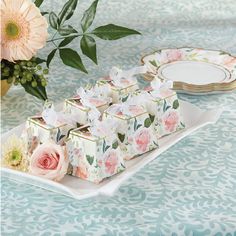 there are many small boxes on the table with flowers and plates in front of them