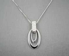 "14 KARAT WHITE GOLD MODERN PENDANT WITH HIGH POLISH . AVAILABLE SAME STYLE EARRINGS metal-14kwg weight-3.4gm FOR ADDITIONAL QUESTIONS ABOUT THIS PRODUCT: Please feel free to message us. We are quick to respond to all your inquiries. PLEASE choose as \"FAVORITE\" on the right so the item will be added to your favorites list and you may always revisit it. CUSTOM ORDERS: Please feel free to contact us if you could not find the piece you had in mind. We know how important it is to find the right je White Gold Oval Necklace With Elegant Design, Oval White Gold Necklace With Elegant Design, White Gold Sterling Silver Diamond Necklace With Oval Pendant, Oval Sterling Silver Diamond Necklace, White Gold Diamond Necklace With Oval Sterling Silver Pendant, Modern White Gold Diamond Necklace With Polished Finish, Fine Jewelry In White Gold With Shiny Finish, Modern Silver Diamond Necklace, Modern White Gold Necklace With Diamond Accents