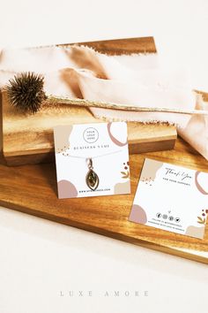 two business cards sitting on top of a wooden tray next to a brush and paper