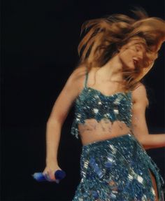 a woman in a blue dress is dancing with her hair blowing back and legs spread out