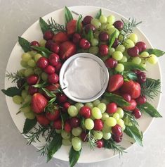 a platter filled with grapes, strawberries and cherries next to a dip