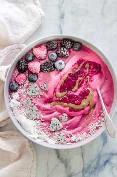 a white bowl filled with berries, blueberries and raspberry ice cream on top of a marble counter