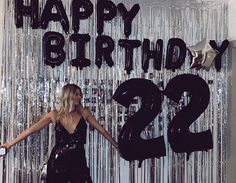 a woman standing in front of a happy birthday sign with the number 22 on it