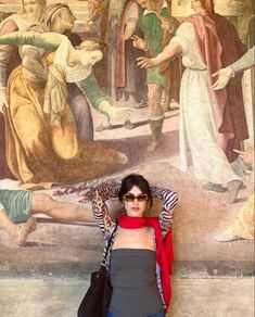 a woman standing in front of a painting with her hands on her head and arms behind her head