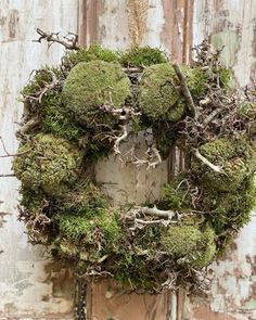 a moss covered wreath hanging on the side of a door