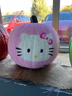 two pumpkins with hello kitty faces painted on them are sitting in front of a window