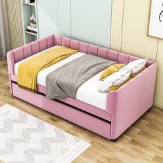 a pink day bed sitting on top of a hard wood floor next to a white rug