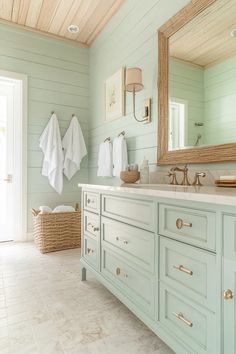 a bathroom with green cabinets and white towels hanging on the wall next to a large mirror