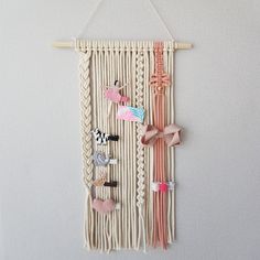 a wall hanging made out of macrame yarn with bows and pins attached to it