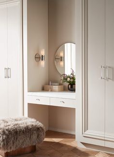 a white dressing table with a stool and mirror on it in a room that has beige walls