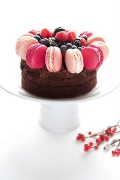 a chocolate cake topped with berries and macaroons