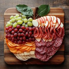 an apple shaped platter with grapes, meats and cheese on it is shown