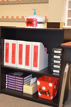 a book shelf filled with books and binders on top of a carpeted floor