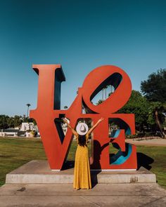 a woman standing in front of the love sculpture