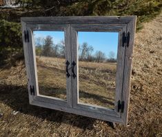 an old wooden cabinet with two mirrors on the front and back sides, sitting in a field