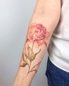 a woman's arm with a pink flower tattoo on the left side of her arm