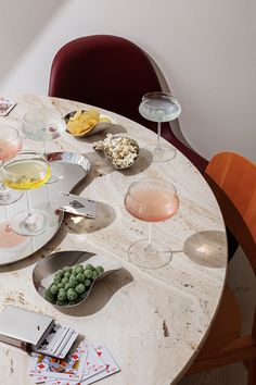 a marble table topped with plates and bowls filled with different types of food next to wine glasses