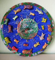 a blue clock with colorful fish and stars on it's face sitting on a table