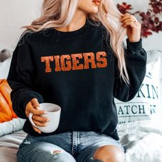 a woman with blonde hair sitting on a couch holding a coffee cup and looking at the camera