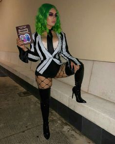 a woman with green hair is holding a book