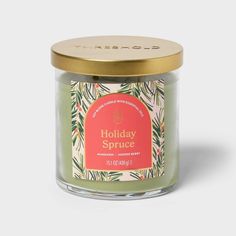 the holiday spice candle is in a glass jar with gold lid and green leaves on it