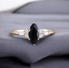 a black and white diamond ring sitting on top of a gray cloth