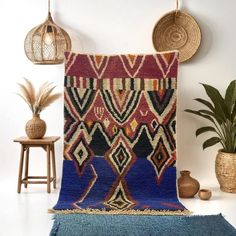 a colorful rug is hanging on the wall next to a potted plant and two wicker baskets