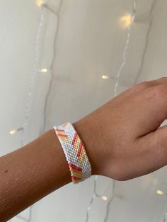 a person's hand with a bracelet on it and lights in the back ground