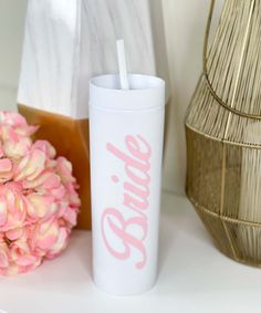 a pink and white tumbler next to some flowers