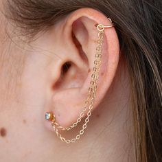 a woman wearing a gold chain ear cuff