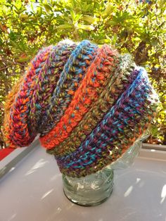 a knitted hat sitting on top of a glass vase