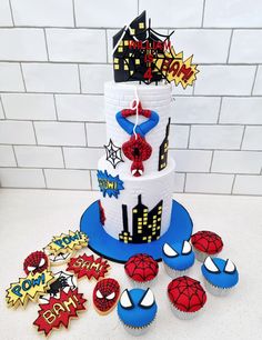 a spiderman themed cake and cupcakes on a table