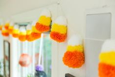 orange and white pom - poms hanging from hooks on the wall in front of a mirror