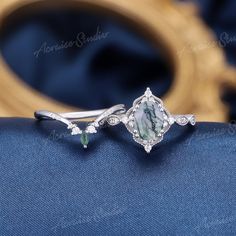 an engagement ring with a green and white stone in the center on a blue cloth