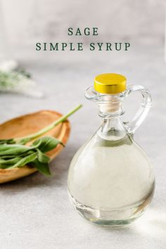 a bottle of sage simples syrup next to a wooden spoon