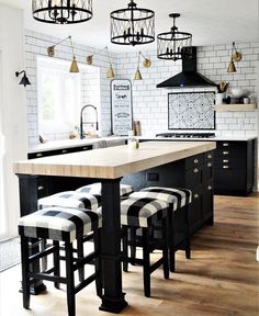 a kitchen with black and white striped stools next to an island in the middle