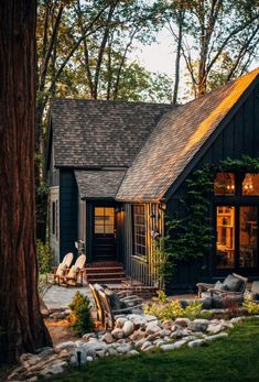 a black house with trees and rocks in the front yard