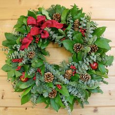 a christmas wreath with poinsettis and greenery on a wooden table top