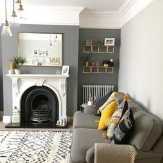 a living room with grey walls and white furniture, including a gray sectional couch in front of a fireplace