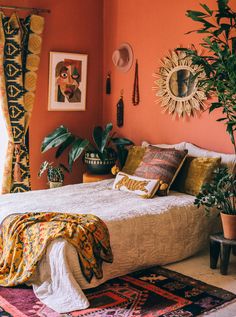 a bedroom with orange walls and plants in the corner, on top of a bed