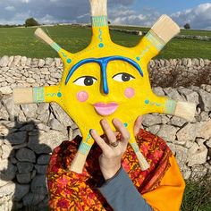 a person holding up a yellow mask in front of their face