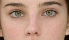 a close up of a woman's face with green eyes