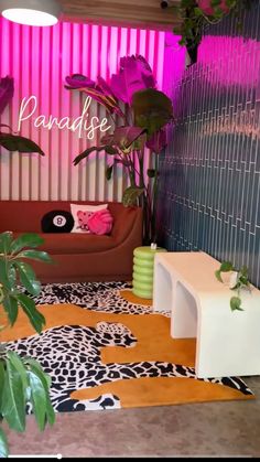 a living room filled with lots of furniture and plants next to a wall covered in pink lights